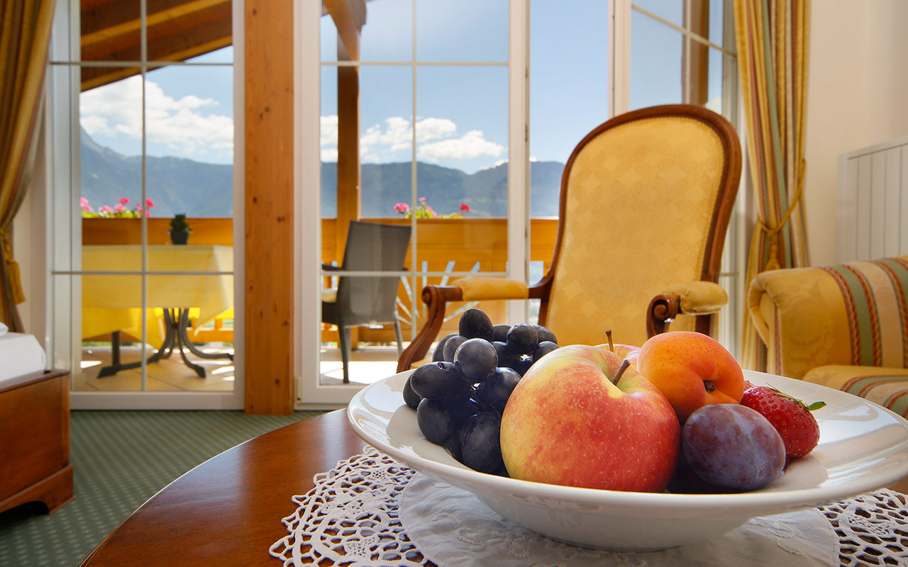 Close-up of a plate with fruit in a room at the Hotel Kristall in South Tyrol with balcony in the background