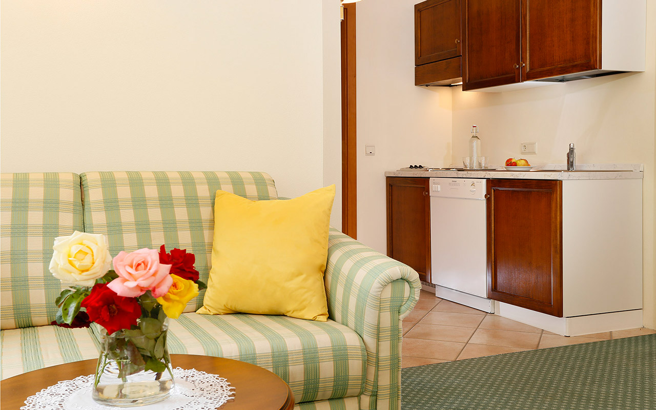 Close-up on the sofa and on the coffee table and little kitchen in the background: an apartment at the Hotel Kristall