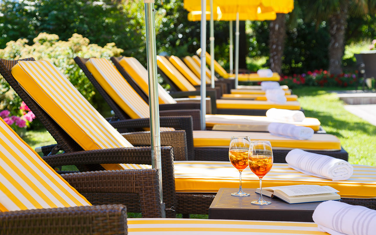 Row of beach chairs and umbrellas in the garden with two drinks on the table
