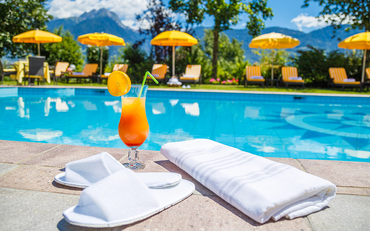 Bordo piscina all'Hotel Kristall: primo piano di asciugamano, ciabatte e cocktail