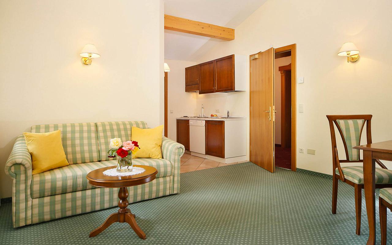 Inside an apartment of Hotel Kristall: sofa and table in the foreground and kitchen in the background