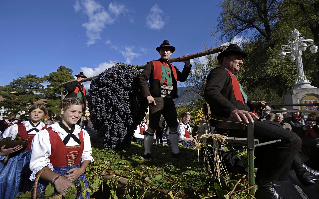 Carro addobbato con uva e persone in abiti tradizionali tirolesi
