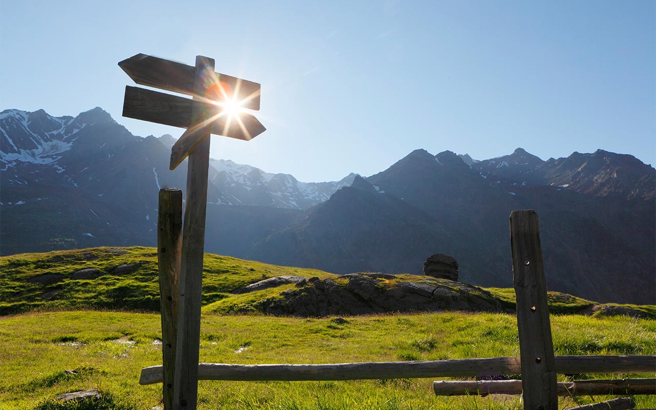 Sonnenaufgang in den Bergen mit Wegweisern für Wanderungen