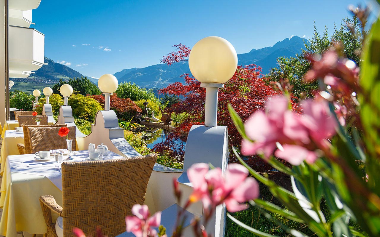 Außenaufnahme des Hotels Kristall: Terrasse mit Tischen, Laternen und Oleandern