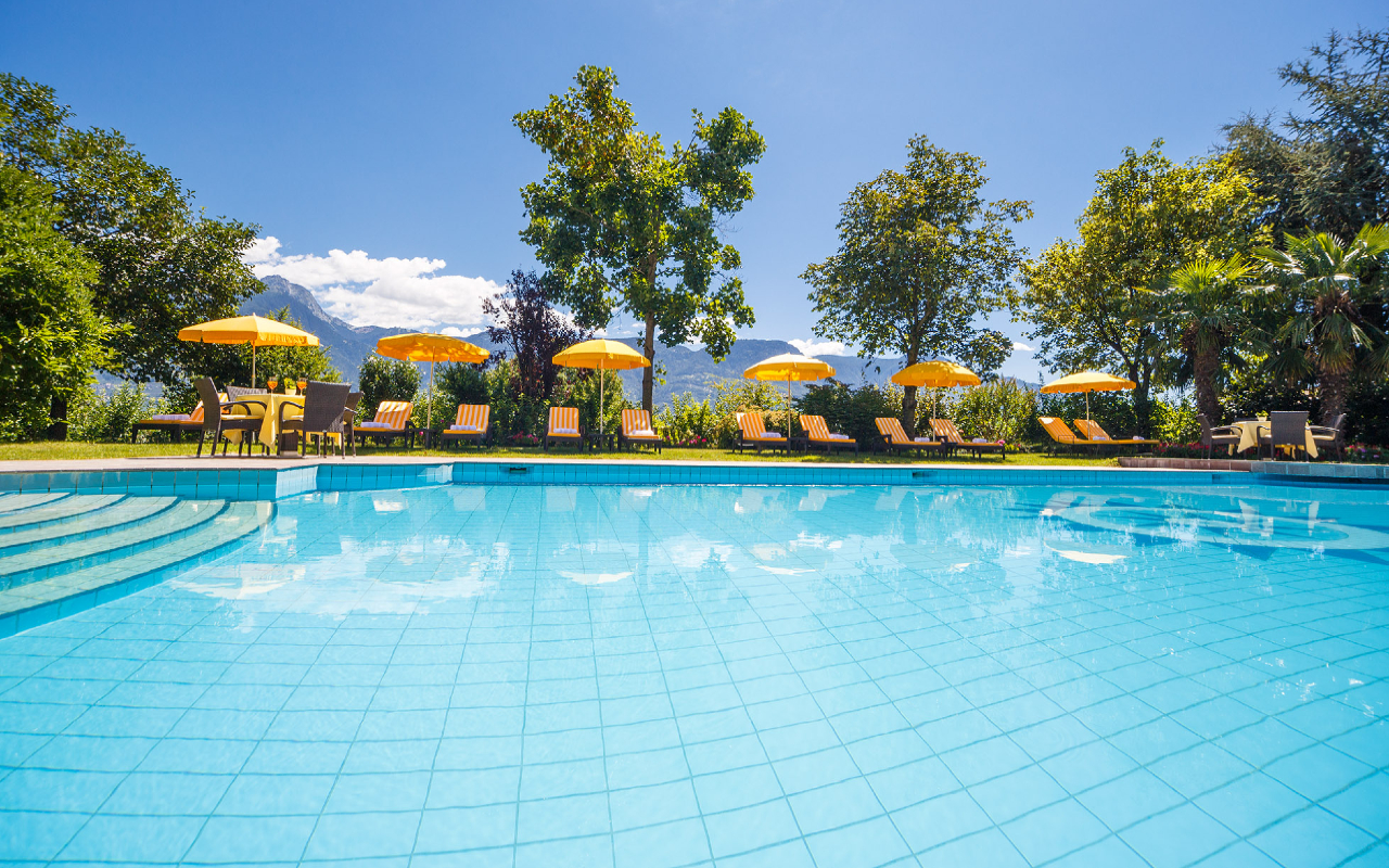 Schwimmbad des Hotels Kristall mit Liegestühlen und Sonnenschirmen am Rand