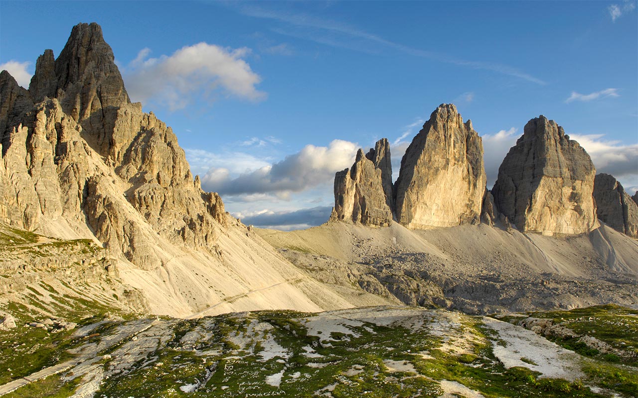 Close-up of the boots of a hiker with poles climbing a path leading to the Three Peaks di Lavaredo