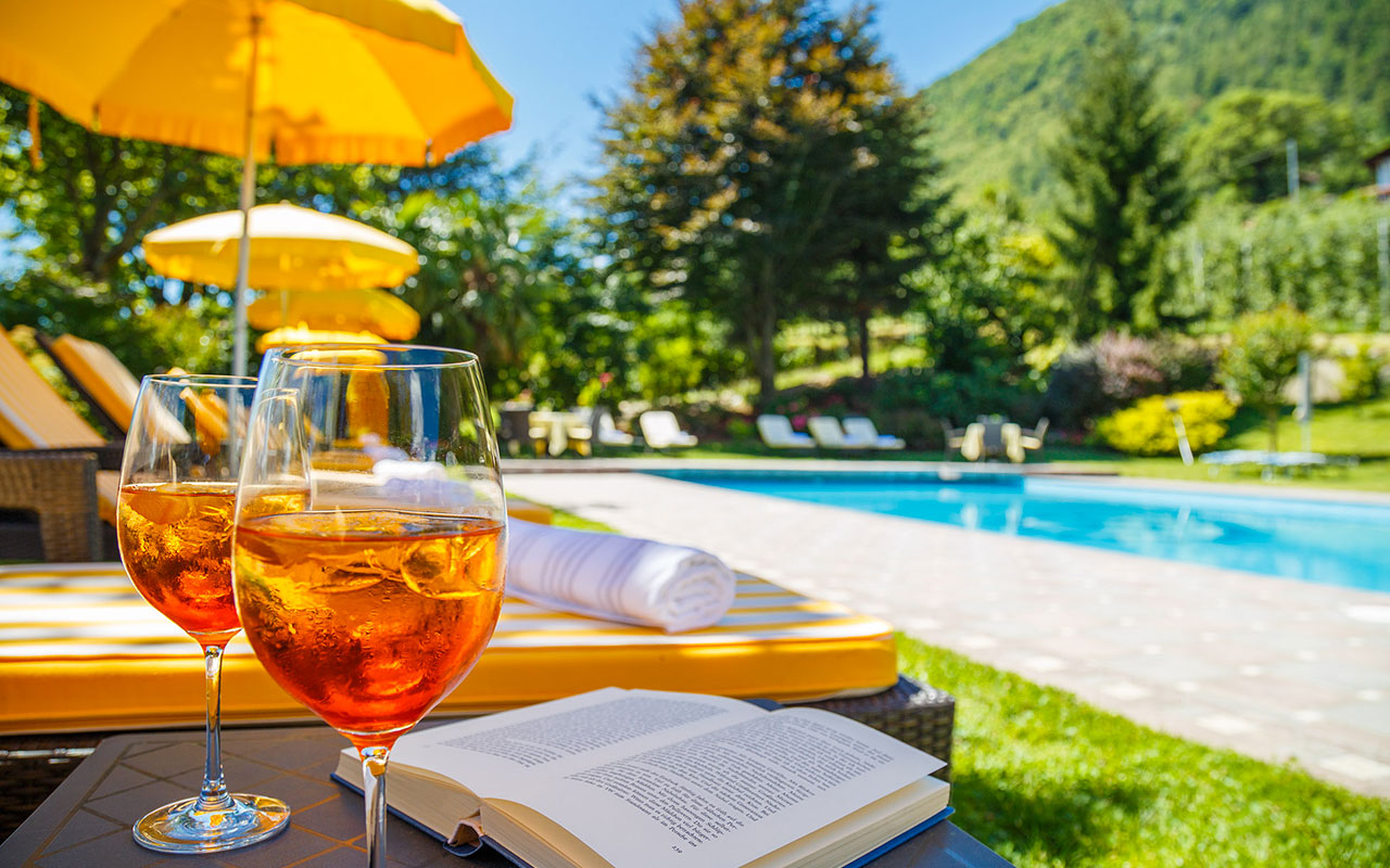 Nahaufnahme zweier Aperol Spritz Gläser am Schwimmbadrand des Hotels Kristall in Marling